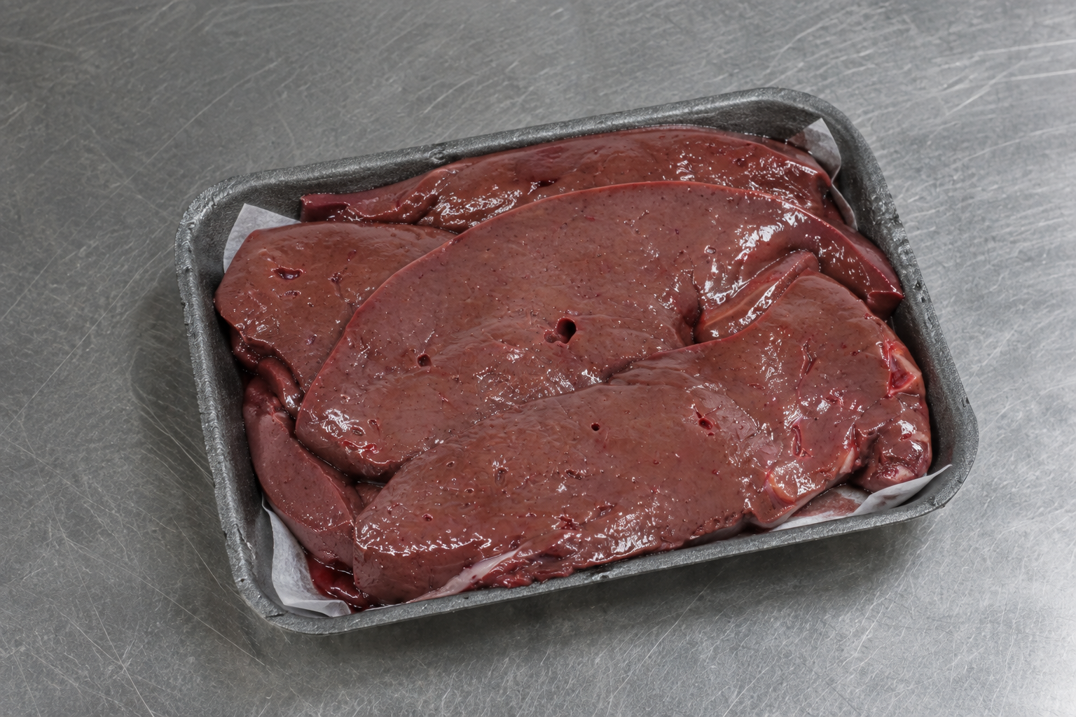 Fresh offal on the counter including liver, kidneys and sliced black pudding